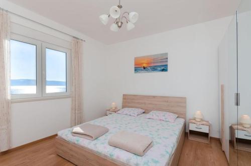 een witte slaapkamer met een bed en 2 ramen bij Apartman Helena in Senj