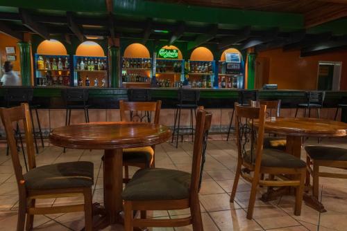 a restaurant with wooden tables and chairs in front of a bar at Sunbird Mzuzu in Katoto