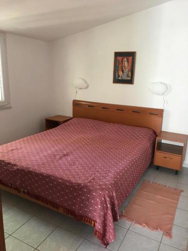 a bedroom with a bed with a red bedspread and two night stands at Apartmani Šehović in Borovići