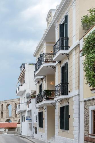 a white building with balconies on a street at The Anthemion House in Kavala