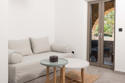 a white living room with a white couch and a table at Calme Suites Mani in Agios Nikolaos