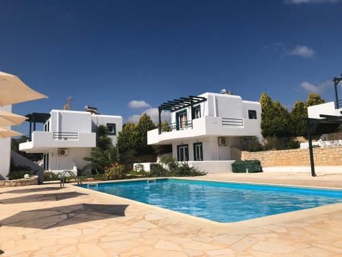 a villa with a swimming pool in front of a house at Cavo Plako Villas in Palekastron