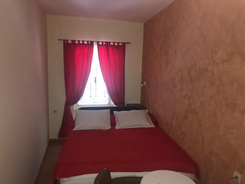a small bedroom with a red bed with a window at Villa Miramare , Dobrota seafront in Kotor