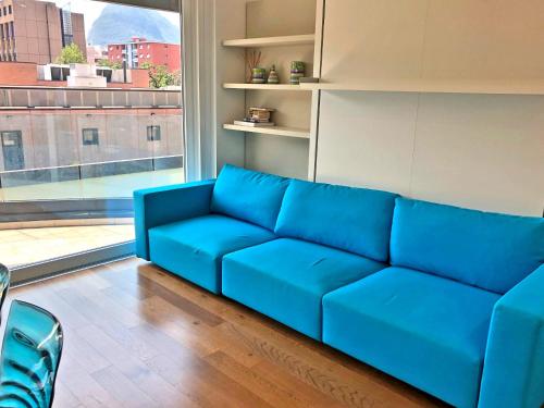 a blue couch in a room with a large window at Roggia Apartments by Quokka 360 - central flats with parking space in Lugano