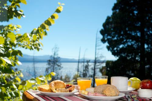 a table with breakfast foods and glasses of orange juice at Pailahue Cabañas Lodge in San Carlos de Bariloche