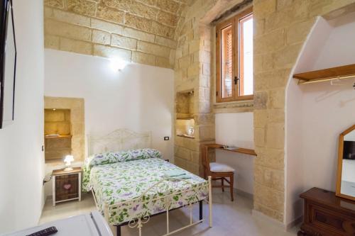 a bedroom with a bed and a desk and a window at Dimora Corte antica in Scorrano