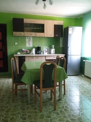 eine Küche mit einem Tisch und Stühlen sowie einem Kühlschrank in der Unterkunft Pensiunea Magura in Baia de Fier