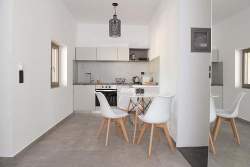 a white kitchen with white chairs and a table at Calme Suites Mani in Agios Nikolaos