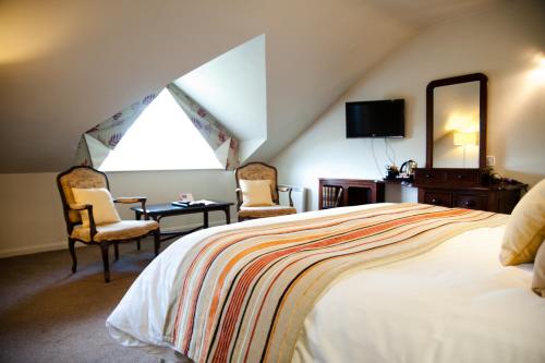 a bedroom with a bed and two chairs and a mirror at Best Western The Dartmouth Hotel, Golf & Spa in Dartmouth
