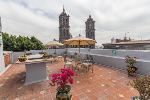 a patio with tables and chairs on a roof with two towers at Hotel Santiago in Puebla