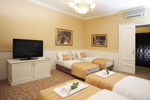 a hotel room with three beds and a flat screen tv at Booking Rooms in Belgrade