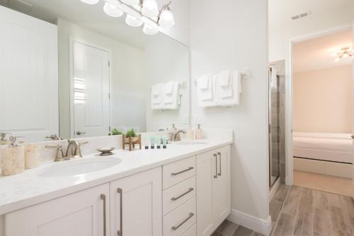 a white bathroom with two sinks and a tub at Striking Home with Games & Outdoor Kitchen near Disney by Rentyl - 7742F in Orlando