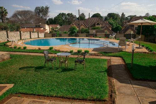 a yard with a table and chairs and a pool at Orchid Homes, Gigiri in Nairobi