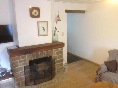 a living room with a brick fireplace and a television at La Truite Joyeuse in Saint-Hubert