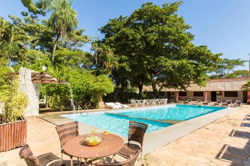 a swimming pool with a table and chairs next to a pool at Hotel Fazenda Mato Grosso in Cuiabá