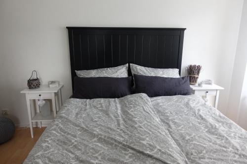 łóżko z czarnym zagłówkiem i dwoma białymi stołami w obiekcie Ver-Reiss-t w mieście Korlingen