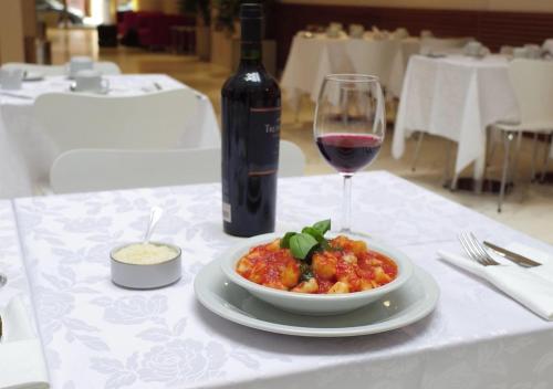 a white table with a bowl of food and a glass of wine at Hotel UOM Buenos Aires in Buenos Aires