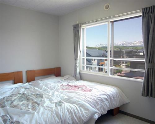 a bedroom with a bed and a large window at Frontier Sunrise in Kami-furano