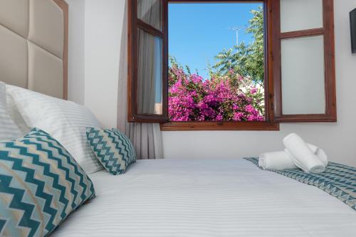a bedroom with a bed with a window and flowers at Pallazzo Fortezza in Rethymno Town