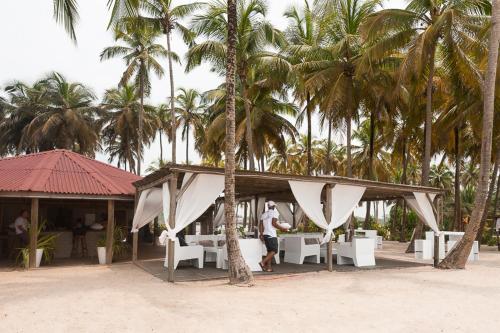 a man standing in front of a resort with palm trees at Hotel Coucoue Lodge in Assinie