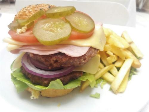 a hamburger with pickles and lettuce and french fries at Hotel UOM Buenos Aires in Buenos Aires