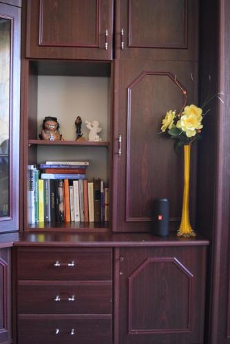 a book shelf with a vase with yellow flowers in it at Cozy self check-in private room in the city centre in Mažeikiai