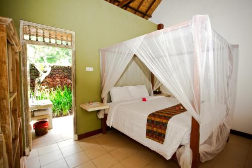 1 dormitorio con 1 cama con mosquitera en D'Tunjung Resort & Spa, en Candidasa