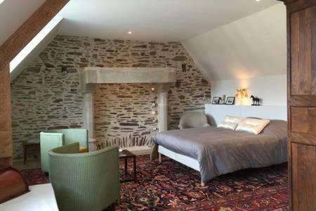 ein Schlafzimmer mit einem Bett und einer Steinmauer in der Unterkunft La Carbonnière in Condé-sur-Vire