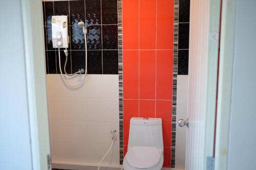 a bathroom with a toilet and orange and black tiles at Khong Chom Jan in Nong Khai