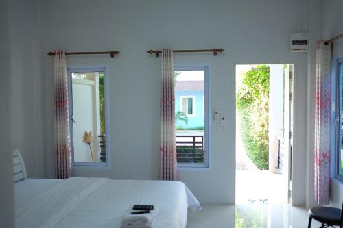 a bedroom with a white bed and a sliding glass door at Khong Chom Jan in Nong Khai