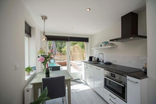 a kitchen with white cabinets and a table with a counter top at The Bond Studio FREE PARKING in Zandvoort