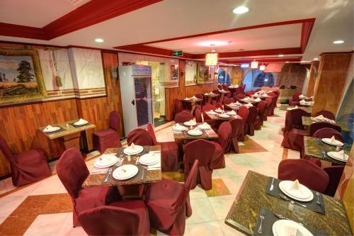 a dining room with tables and red chairs in a restaurant at Manazeli Madinah in Medina