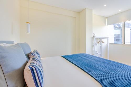 um quarto branco com uma cama e uma janela em Trindade Modern Flat no Porto