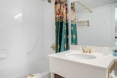 Coachman Inn في كيتري: حمام أبيض مع حوض وحوض استحمام