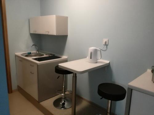 una pequeña cocina con fregadero y 2 taburetes en hostel52, en Gdansk