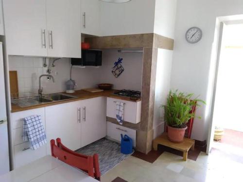 una piccola cucina con armadi bianchi e una sedia rossa di Apartamento sobre o Rio a Lisbona