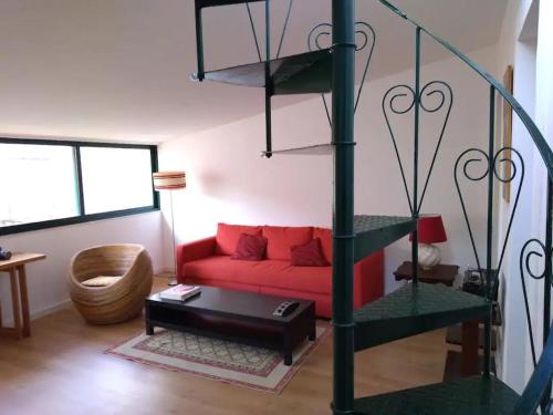 a living room with a red couch and a spiral staircase at Apartamento sobre o Rio in Lisbon