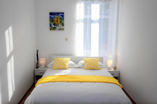 a bedroom with a bed with yellow and white sheets at Bivium in Otočac