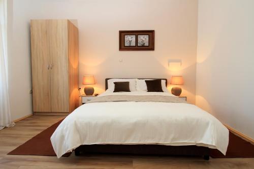 a bedroom with a large white bed with two lamps at Bivium in Otočac