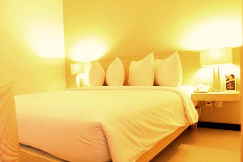 a bedroom with a large white bed and a phone at Hotel Santika Bengkulu in Bengkulu