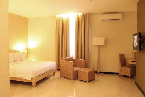 a hotel room with a bed and a chair and a window at Hotel Santika Bengkulu in Bengkulu