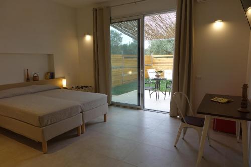 a bedroom with a bed and a table and a patio at giardino del tempo in Merine