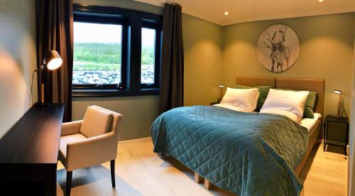 a bedroom with a bed and a chair and a window at Lyngen Experience Lodge in Nord-Lenangen