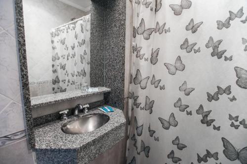 y baño con lavabo y cortina de ducha con mariposas. en Novel Hotel en Buenos Aires