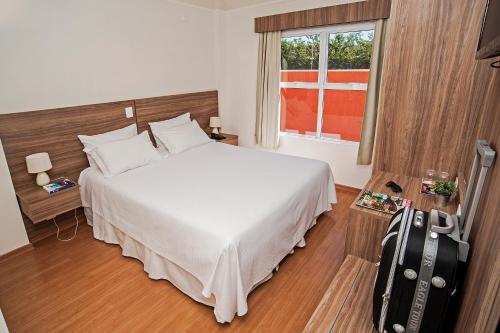 una habitación de hotel con una cama y una maleta en The Hill Hotéis Executive, en São Carlos