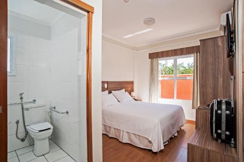 a bedroom with a bed and a shower and a toilet at The Hill Hotéis Executive in São Carlos