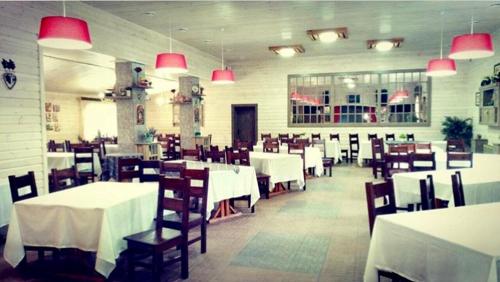 una sala da pranzo con tavoli bianchi e sedie in legno di Hotel Bannyi Dvor a Uzyn
