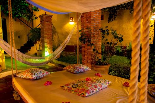 una cama con almohadas y una hamaca en una habitación en Hotel Casa Alvarada, en Comala