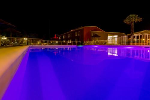 a swimming pool lit up in blue lights at night at ibis Montélimar Nord in Saulce-sur-Rhône