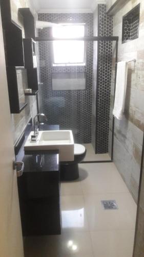 uma casa de banho com um lavatório e um chuveiro com um WC. em Apartamento Enseada LC01 no Guarujá